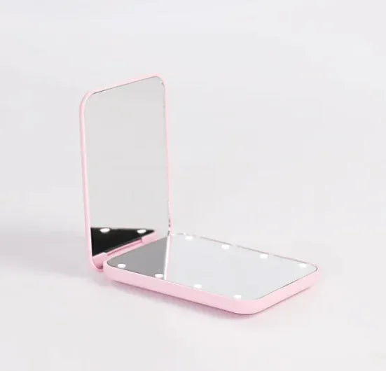 Foldable GlowFold LED makeup mirror on pink background showing bright LED lights