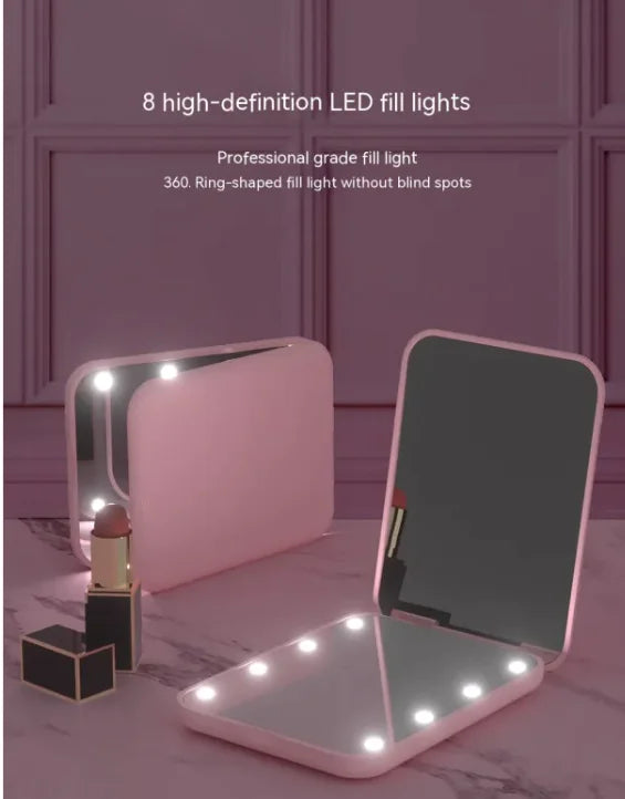 Pink GlowFold foldable LED makeup mirror with 8 LED fill lights on vanity with lipstick